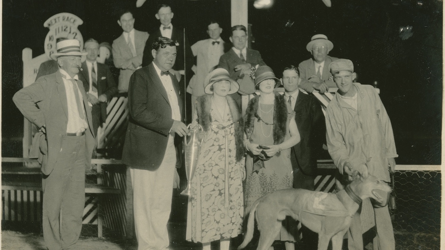 1925年，佛罗里达州圣彼得堡的德比巷灰狗赛车场，棒球传奇人物贝比·鲁斯与其他观众一起在获胜的灰狗比赛坡道上合影留念。